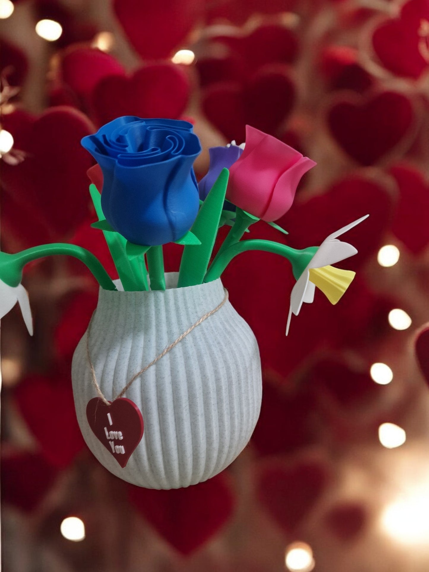 flower pot with red silk rose, two additional roses, two daffodils, love heart pendants reading 'I Love You' and 'Happy Motherās Day', and a cute bee. Dimensions: 28cm (H) x 18cm (W) x 18cm (D). Perfect for Motherās Day or Valentineās Day, a lasting gift that doesnāt wilt.