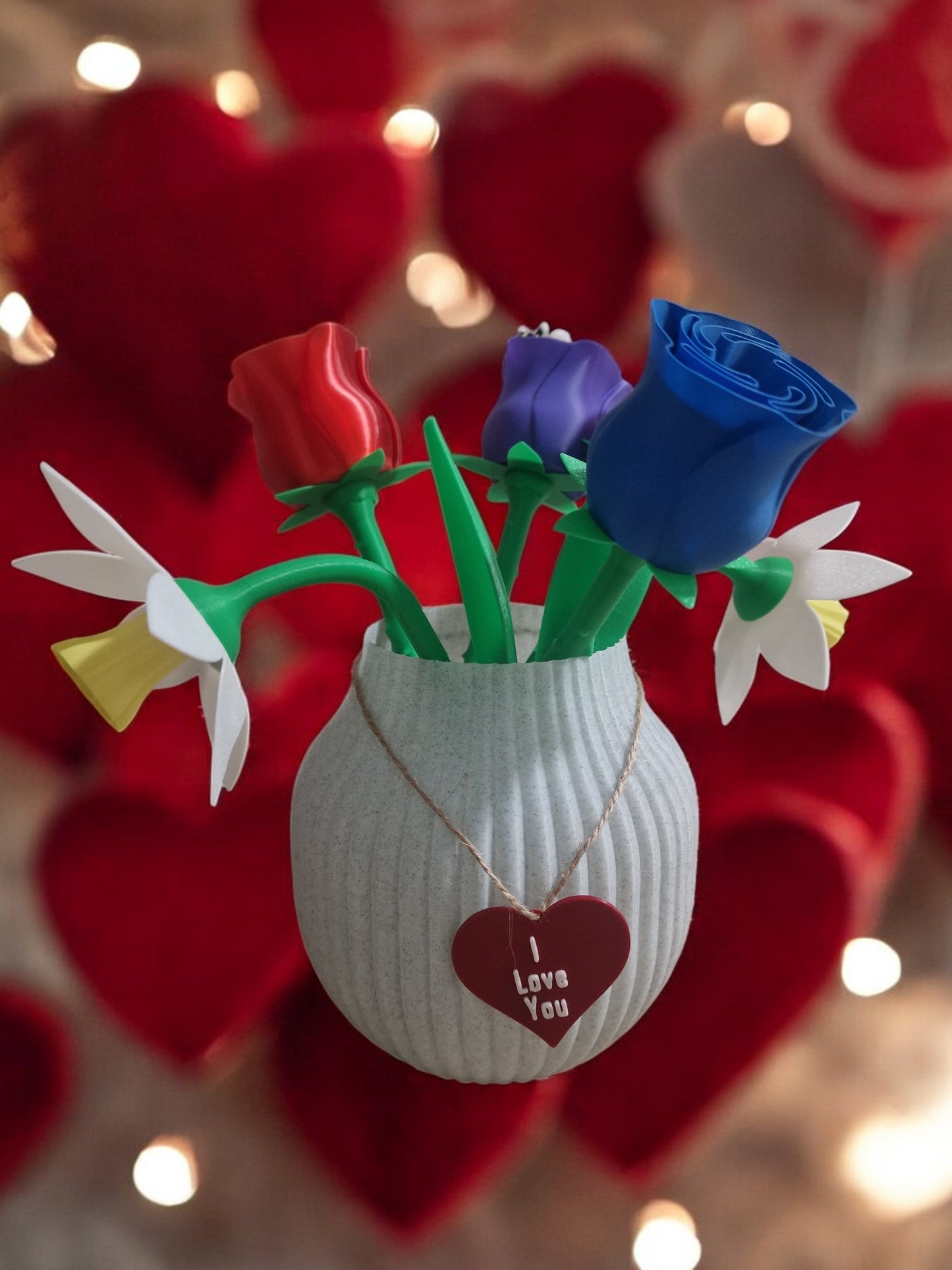 flower pot with red silk rose, two additional roses, two daffodils, love heart pendants reading 'I Love You' and 'Happy Motherās Day', and a cute bee. Dimensions: 28cm (H) x 18cm (W) x 18cm (D). Perfect for Motherās Day or Valentineās Day, a lasting gift that doesnāt wilt.