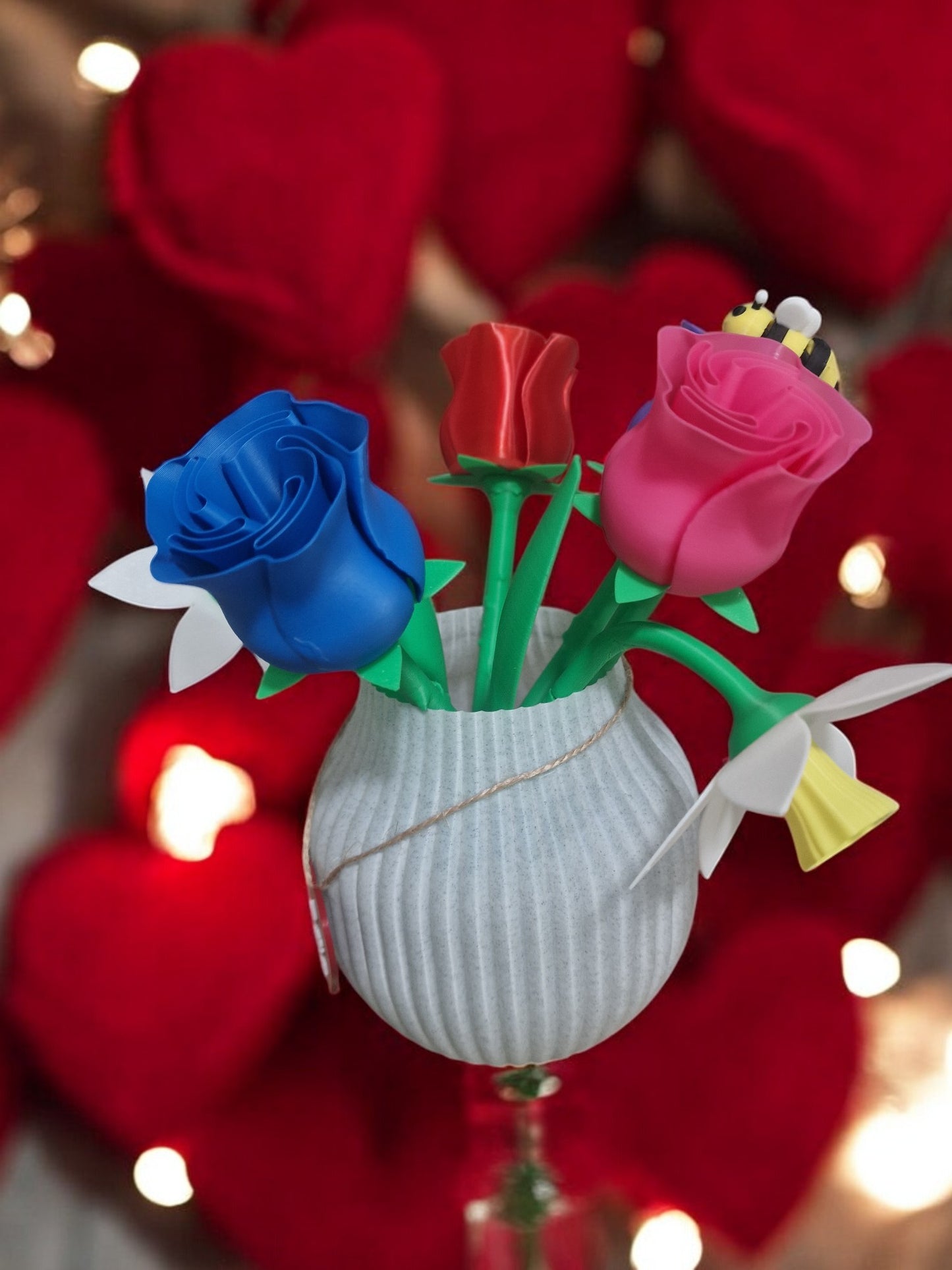 flower pot with red silk rose, two additional roses, two daffodils, love heart pendants reading 'I Love You' and 'Happy Motherās Day', and a cute bee. Dimensions: 28cm (H) x 18cm (W) x 18cm (D). Perfect for Motherās Day or Valentineās Day, a lasting gift that doesnāt wilt.