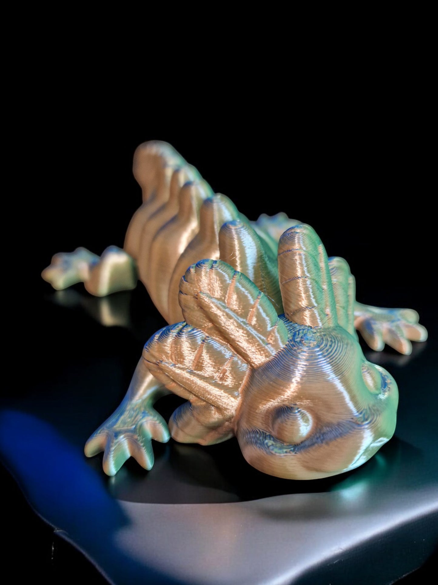 A 3D-printed articulating axolotl figurine with movable limbs and tail, measuring 9cm long, 4cm wide, and 3cm high. This durable, lightweight piece features a random dual-tone color design, making it a playful and unique display item or gift for axolotl enthusiasts and collectors.