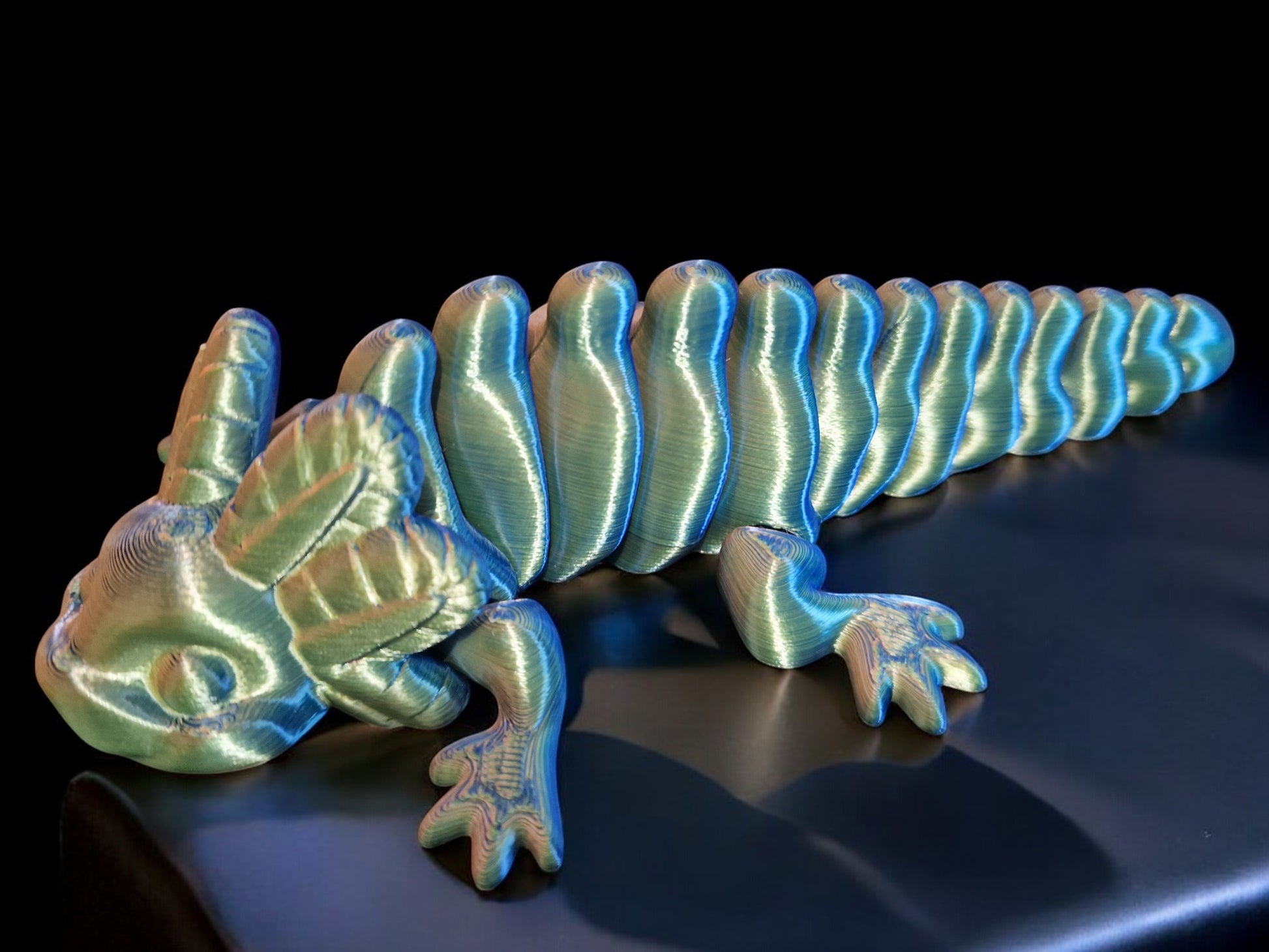 A 3D-printed articulating axolotl figurine with movable limbs and tail, measuring 9cm long, 4cm wide, and 3cm high. This durable, lightweight piece features a random dual-tone color design, making it a playful and unique display item or gift for axolotl enthusiasts and collectors.