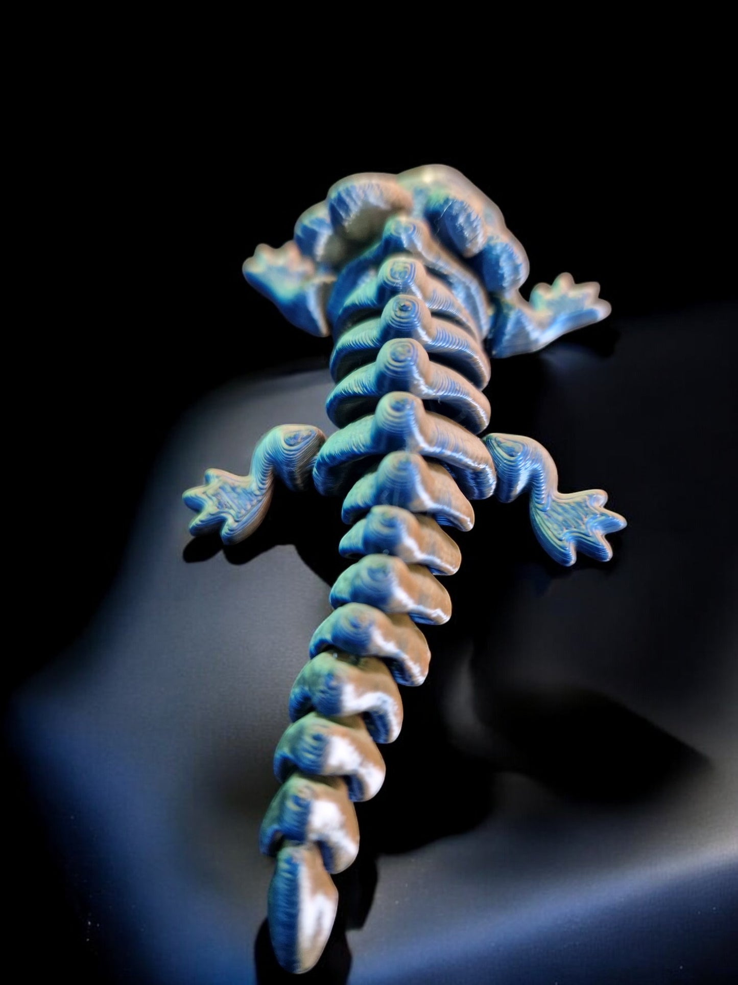 A 3D-printed articulating axolotl figurine with movable limbs and tail, measuring 9cm long, 4cm wide, and 3cm high. This durable, lightweight piece features a random dual-tone color design, making it a playful and unique display item or gift for axolotl enthusiasts and collectors.