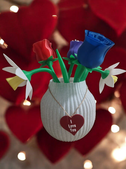 flower pot with red silk rose, two additional roses, two daffodils, love heart pendants reading 'I Love You' and 'Happy Mother’s Day', and a cute bee. Dimensions: 28cm (H) x 18cm (W) x 18cm (D). Perfect for Mother’s Day or Valentine’s Day, a lasting gift that doesn’t wilt.