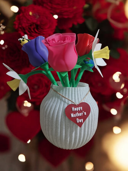 flower pot with red silk rose, two additional roses, two daffodils, love heart pendants reading 'I Love You' and 'Happy Mother’s Day', and a cute bee. Dimensions: 28cm (H) x 18cm (W) x 18cm (D). Perfect for Mother’s Day or Valentine’s Day, a lasting gift that doesn’t wilt.
