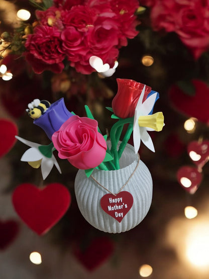 flower pot with red silk rose, two additional roses, two daffodils, love heart pendants reading 'I Love You' and 'Happy Mother’s Day', and a cute bee. Dimensions: 28cm (H) x 18cm (W) x 18cm (D). Perfect for Mother’s Day or Valentine’s Day, a lasting gift that doesn’t wilt.
