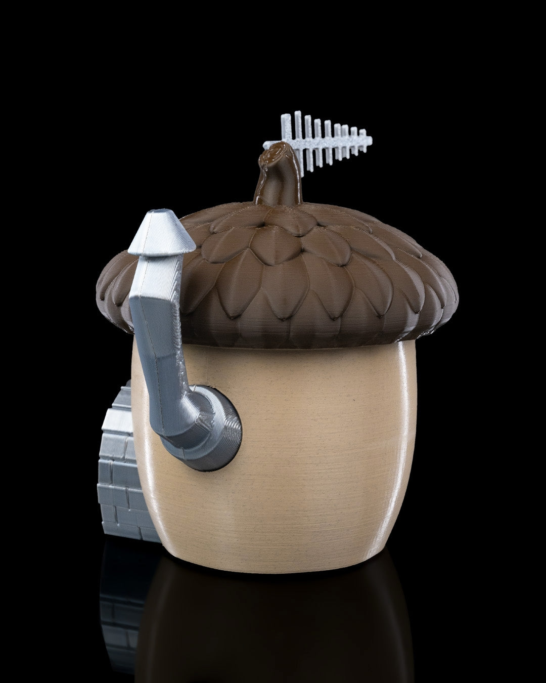 A charming acorn-shaped house decoration featuring a textured brown roof, circular window, wooden door with silver accents, and a chimney. Perfect for gardens, small pet enclosures, or reptile terrariums, set against a natural backdrop of green plants