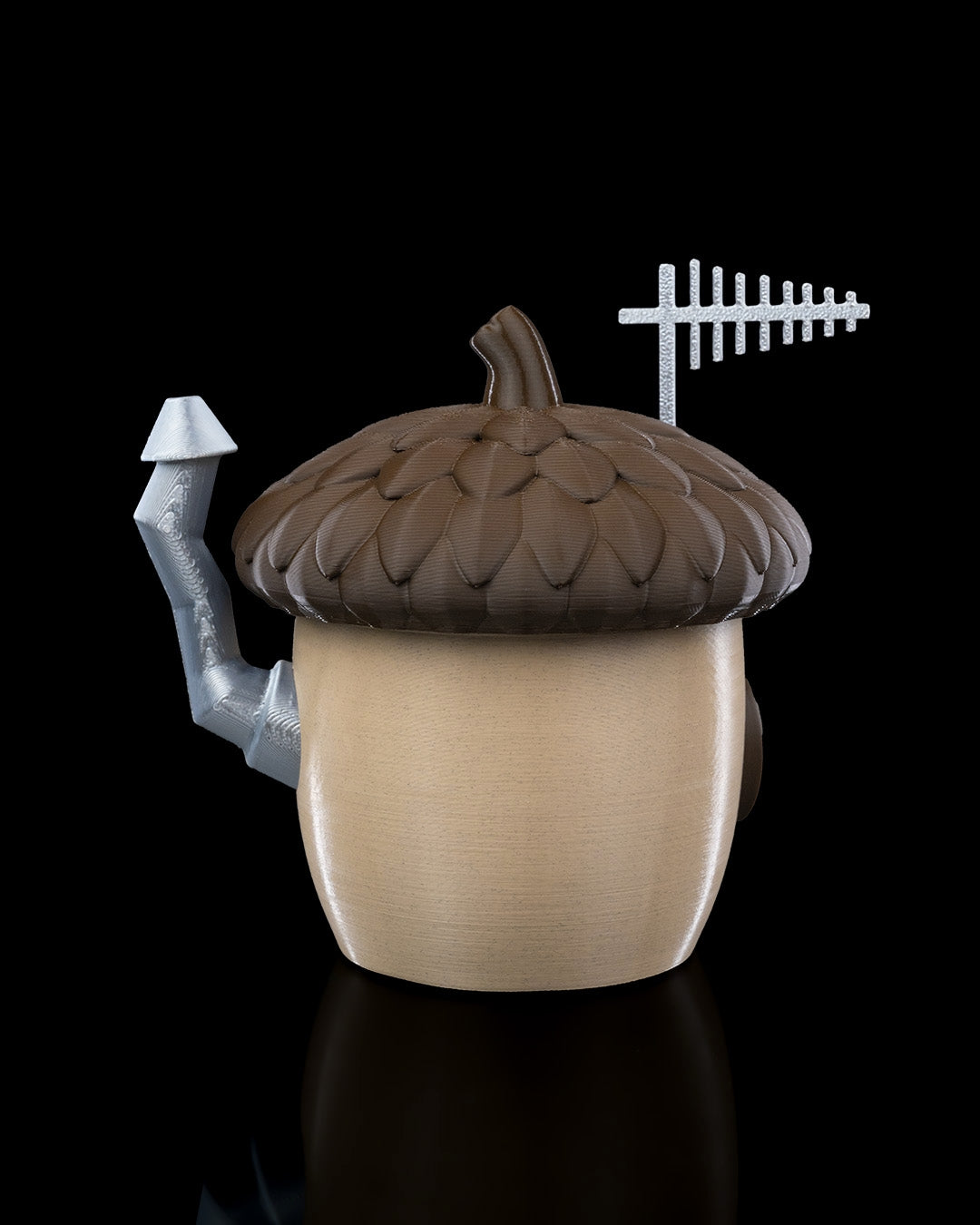 A charming acorn-shaped house decoration featuring a textured brown roof, circular window, wooden door with silver accents, and a chimney. Perfect for gardens, small pet enclosures, or reptile terrariums, set against a natural backdrop of green plants